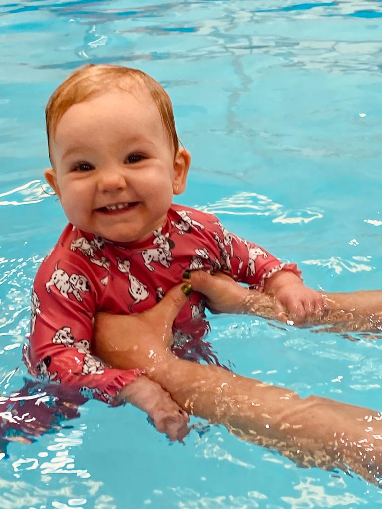 A happy, confident baby smiling while swimming in the pool