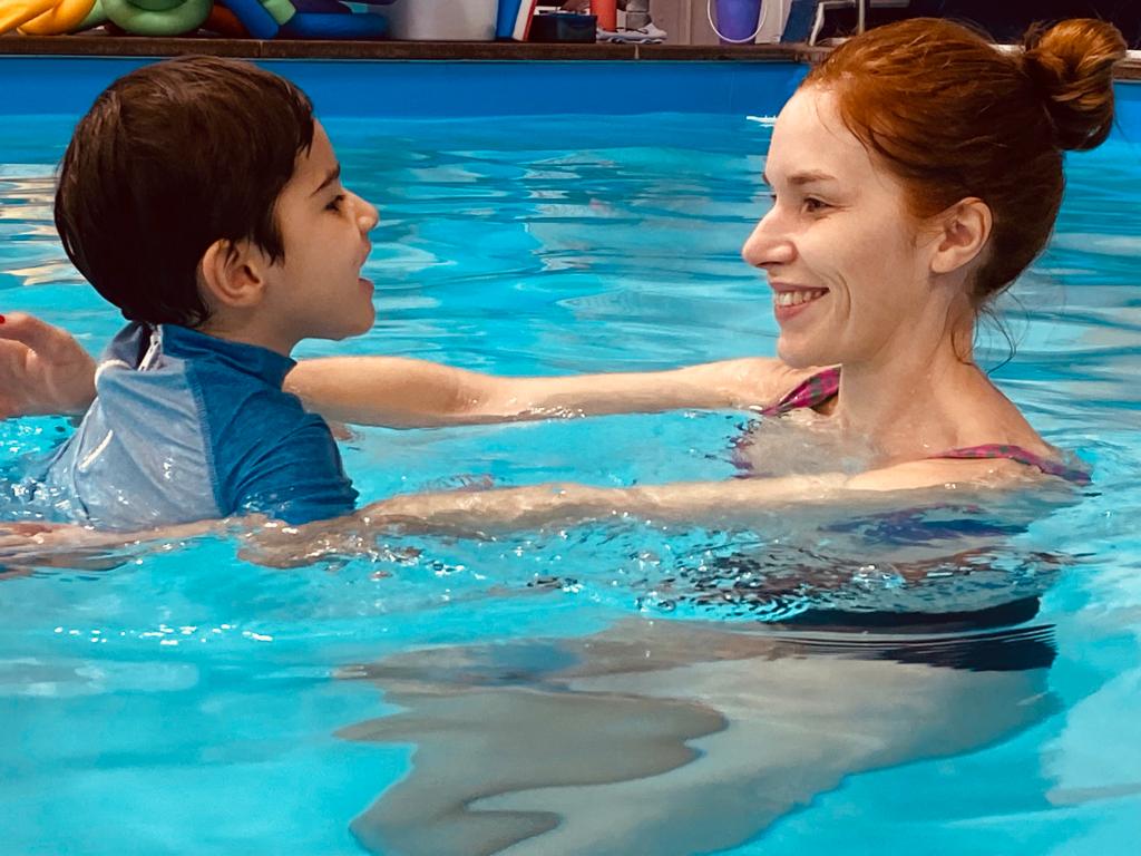 A swim teacher and child smiling at each other during a lesson
