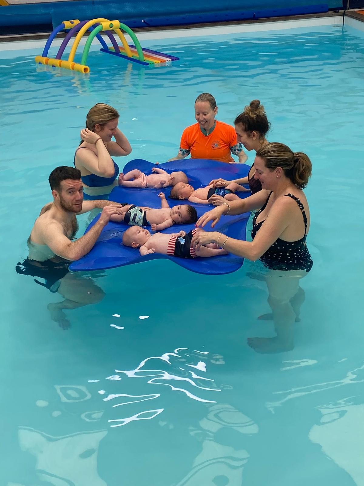 Parents and babies laughing together at a Happy Tiddlers swim session